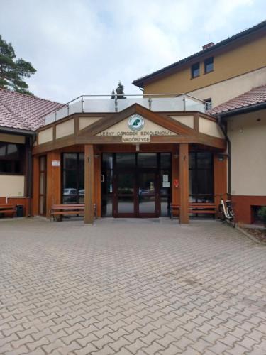 a building with a large entrance with benches in front at Leśny Ośrodek Szkoleniowy Nagórzyce in Swolszowice Małe