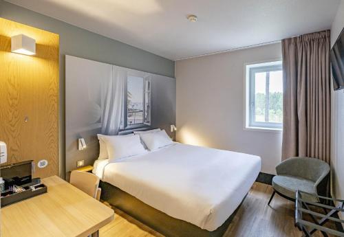 a hotel room with a large bed and a desk at B&B HOTEL Arcachon Gujan-Mestras in Gujan-Mestras