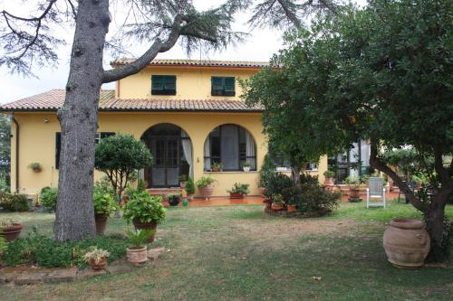 a yellow house with trees and plants in a yard at Tenuta Poggio alla Farnia in Fauglia