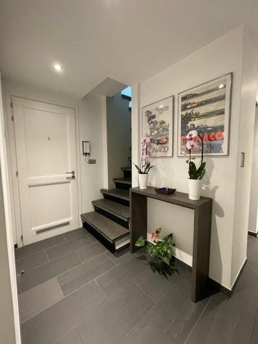 un couloir avec une porte blanche et des escaliers avec des plantes en pot dans l'établissement 3 bedrooms Duplex penthouse - Monaco border 2min walking distance, à Roquebrune-Cap-Martin