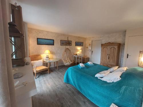 a bedroom with a large bed with a blue blanket at Retour aux Sources in Gouberville
