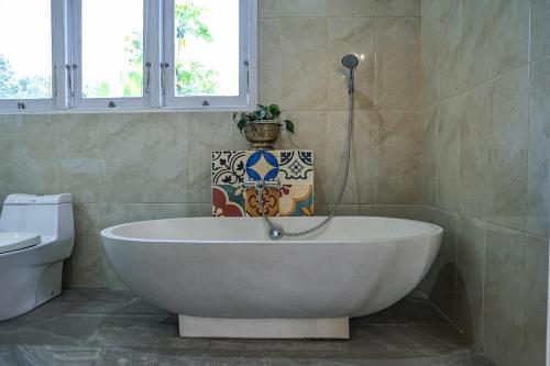 y baño con bañera, aseo y jarrón. en Casarita Villa Jogja, en Jarakan