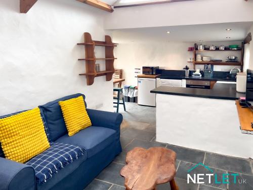 a living room with a blue couch and a kitchen at Ty Bedwen - Cosy Rural Retreat in St Davids in St. Davids