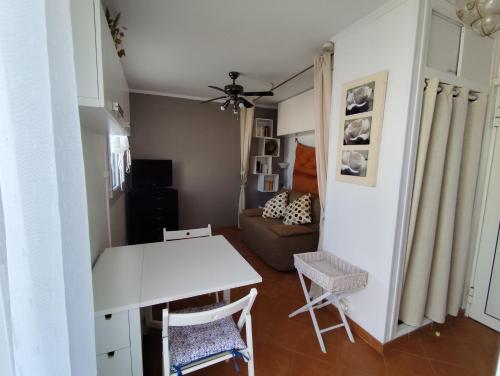 un salon avec une table et des chaises blanches dans l'établissement Studio avec terrasse face plage parking, au Barcarès