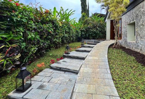 a stone walkway with benches in a garden at Villa Klub Bunga - by The Batu Hotel Batu Malang in Batu