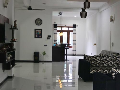 a living room with a couch and a clock on the wall at Aqua Breeze Villa in Ja-Ela