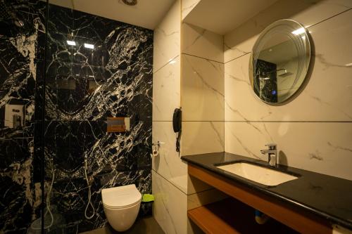 a bathroom with a sink and a toilet and a mirror at West Bay MARISOL in Varkala