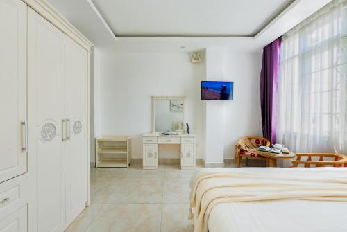 a white bedroom with a bed and a desk at AM Memory Central Hotel 2 in Da Lat