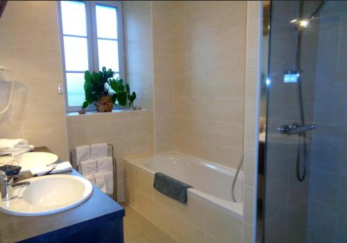 a bathroom with a tub and a sink and a shower at Logis Hotel Restaurant La Croisée des Chemins in Cayres