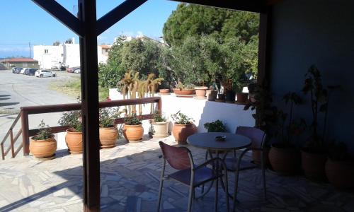 a patio with a table and chairs and potted plants at Pension Kyriakos in Plakias