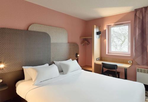 a bedroom with a large white bed and a window at B&B HOTEL Noisy-le-Grand in Noisy-le-Grand