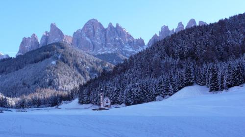 a mountain with a house in the middle of a snow covered field at Haus Tannenburg in Funes