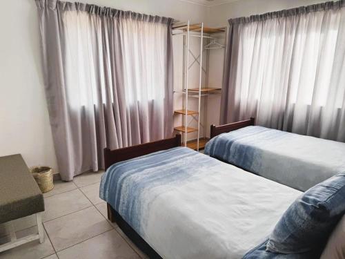 a bedroom with two beds and a window with curtains at Oupa Gallie in Vleesbaai in Vleesbaai