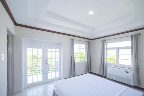 a white bedroom with a bed and two windows at St Silas 3-bedroom by ZenBreak in Saint James