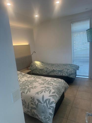 a bedroom with two beds in a room with a window at Palm Breeze Getaway-Waiheke Island Resort Premium 95m Villa in Waiheke Island