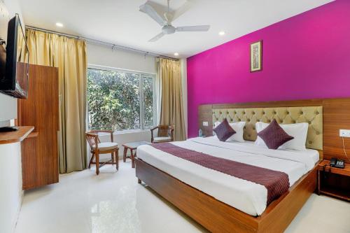 a bedroom with a large bed with a pink wall at La Olivia in Haridwār