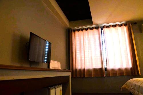ein Fernseher, der auf einem Kaminsims neben einem Fenster steht in der Unterkunft Baan Kieng Guest House Lampang in Lampang