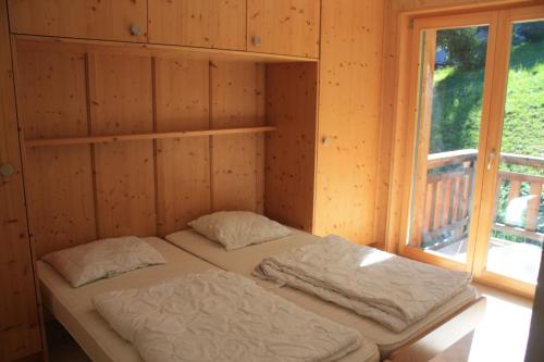 Una cama en una habitación de madera con ventana. en Plein Ciel VA 030 - MOUNTAIN apartment 8 pers, en Veysonnaz
