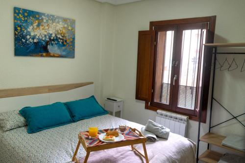 a bedroom with a bed and a table with food on it at El Refugio de Doña Jimena in Burgos