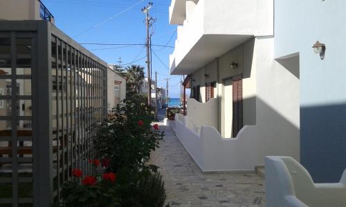 a narrow alley with white buildings and red flowers at Pension Kyriakos in Plakias