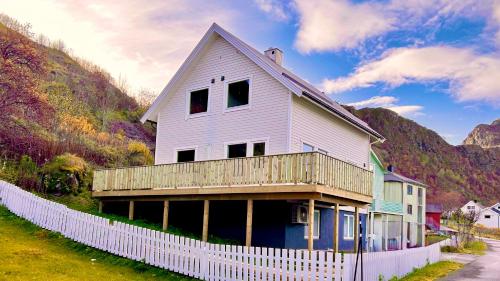 a white house with a fence in front of it at Sandersstua 2, luxury family apartment with private whirlpool in Stamsund in Vestvågøya