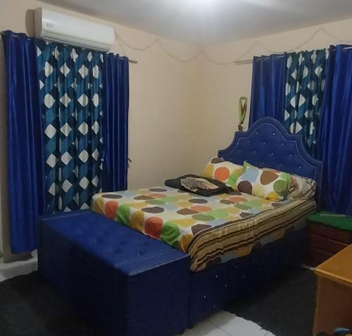 a bedroom with a blue bed with blue curtains at Charming Piarco Home with Garden View in Piarco
