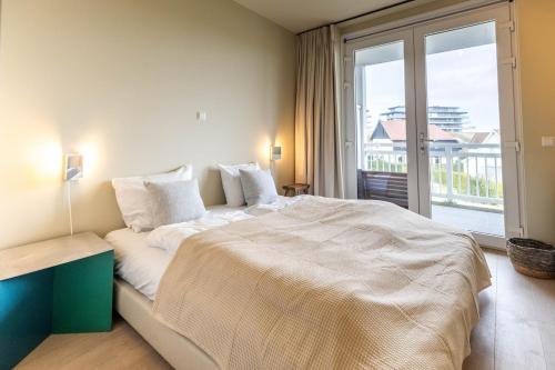 a bedroom with a large bed and a large window at Mare by Room of in Cadzand