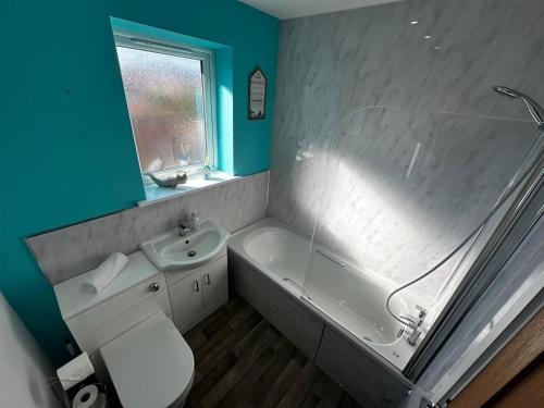 a bathroom with a toilet and a tub and a sink at Sunny 2-Bedroom Coastal Stay with Free Parking in Great Yarmouth