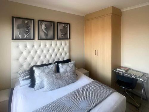 ein Schlafzimmer mit einem weißen Bett mit großem Kopfteil in der Unterkunft Capricon Village 3 Bedroom Villa in Centurion