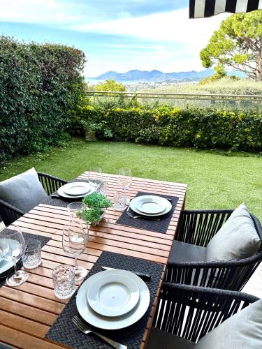 a wooden table with plates and wine glasses on it at Garden sea view - Victoria - Le Cannet in Le Cannet