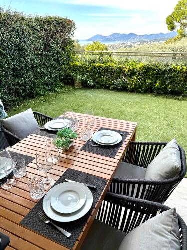 a wooden table with plates and wine glasses on it at Garden sea view - Victoria - Le Cannet in Le Cannet