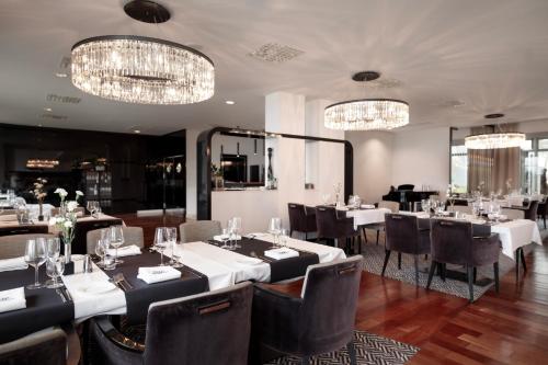 a dining room with tables and chairs and chandeliers at Diune Hotel by Zdrojowa in Kołobrzeg