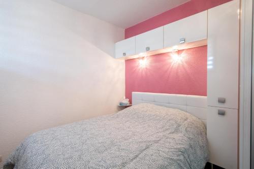 une chambre avec un lit et un mur rouge dans l'établissement Escale au Boucanet - A 150m de la plage, au Grau-du-Roi