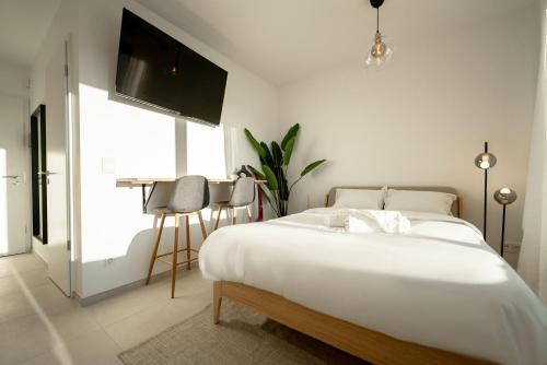a bedroom with a large white bed and a table at Modern Studio in Gasperich with Balcony & Wi-Fi in Luxembourg