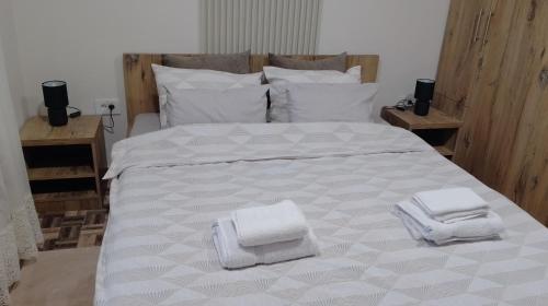 a large white bed with two towels on it at Apartman Dve lipe in Palić