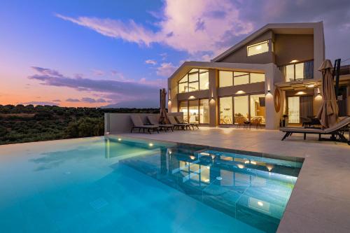 a house with a swimming pool in front of a house at Theo Luxury Villas With Sea View in Agia Marina Nea Kydonias