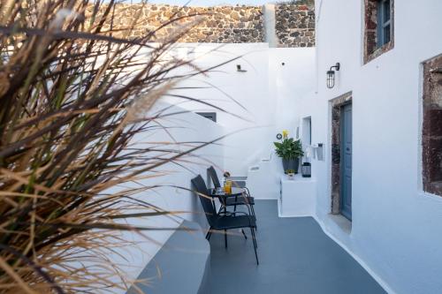 a hallway with white walls and a table and chairs at Noelia Suites in Oia