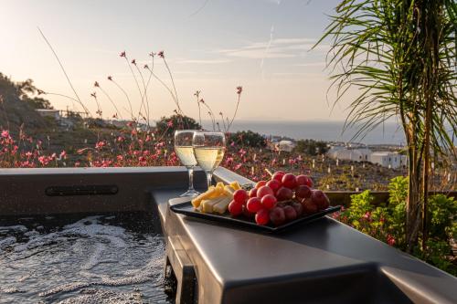 a plate of fruit and a glass of wine on a table at Noelia Suites in Oia