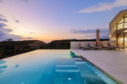 an outdoor swimming pool with chairs and a house at Theo Luxury Villas With Sea View in Agia Marina Nea Kydonias