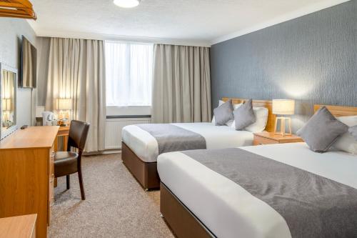 a hotel room with two beds and a desk at Airport Hotel Manchester in Manchester
