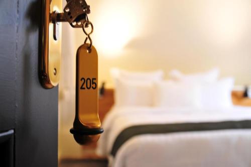 a hotel room door with a tag on it with a bed at Les Glycines Vézelay in Vézelay