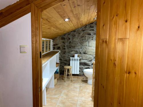 a bathroom with a toilet and a stone wall at Casa Los Josuco in Collado