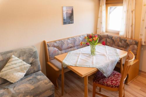 a table and a couch with a vase of flowers on it at Pension Trillerhof in Ramsau am Dachstein