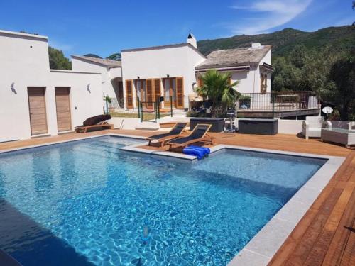 a swimming pool with chairs and a house at Maison d'exception au Cap Corse in Luri