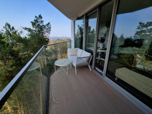 a balcony with a chair and a table on it at PINEA Apartments Pobierowo z niesamowitym widokiem na morze oraz jacuzzi w wybranych apartamentach in Pobierowo