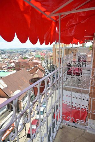 a balcony with a red umbrella and a view of a city at Hotel Brajas in Antananarivo