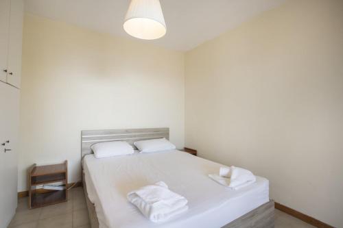 ein weißes Schlafzimmer mit einem Bett mit zwei Handtüchern darauf in der Unterkunft Eria Home by RentalsPro - Trikorfo Halkidiki in Yerakiní