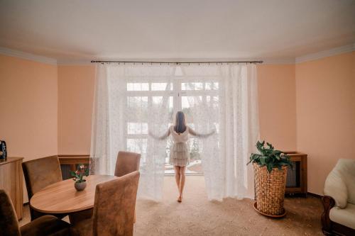a woman in a white dress walking through a window at Hotel Solisko in Štrbské Pleso