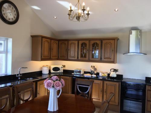 a kitchen with wooden cabinets and a table with flowers at Ballintoy old school house in Ballintoy