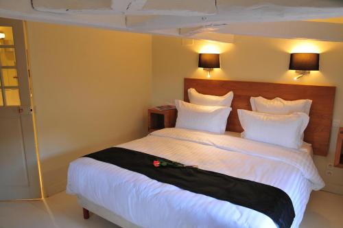 a bedroom with a large bed with white sheets and pillows at Les Glycines Vézelay in Vézelay